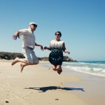 Baby boomer retired couple jumping for joy on beach